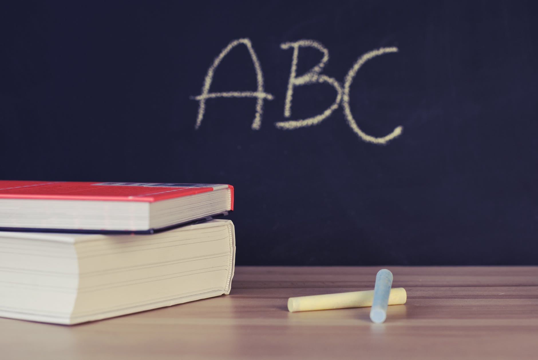 picture of "A B C" written on a chalk board with books in the foreground.